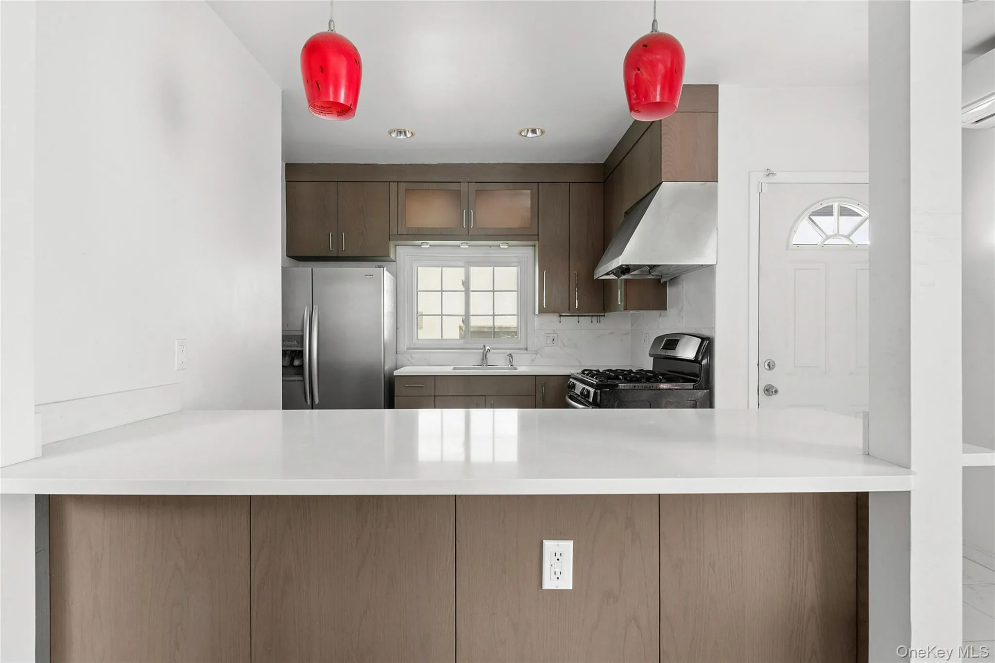 Kitchen featuring a white Quartz countertop, wood-finish cabinetry, stainless steel refrigerator, and a built-in range with a stainless steel vent hood Kitchen featuring a white Quartz countertop, wood-finish cabinetry, stainless steel refrigerator, and a built-in range with a stainless steel vent hood