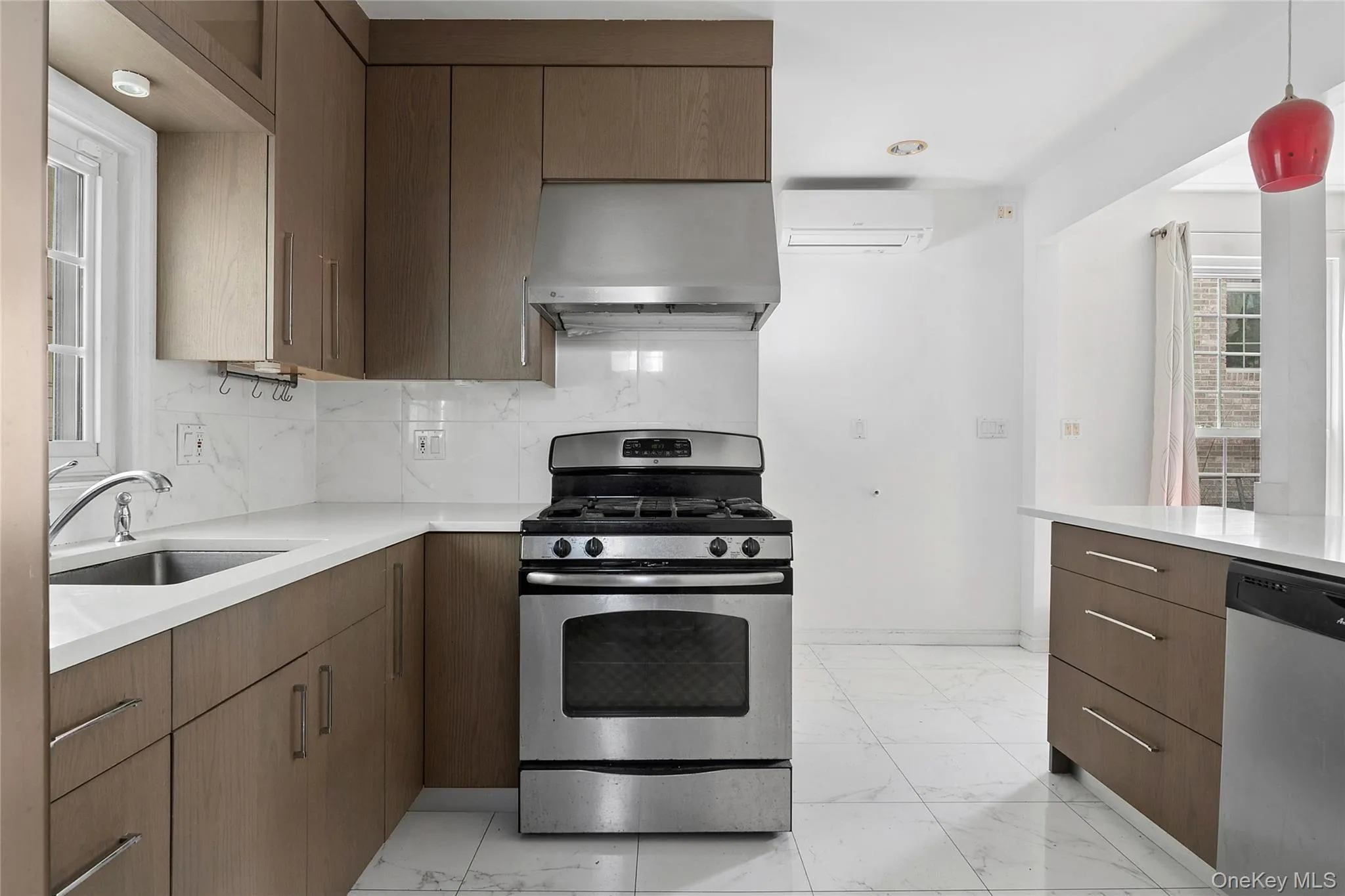 Kitchen featuring wood-finish cabinetry, stainless steel appliances, white Quartz countertops, and a full-height tile backsplash Kitchen featuring wood-finish cabinetry, stainless steel appliances, white Quartz countertops, and a full-height tile backsplash