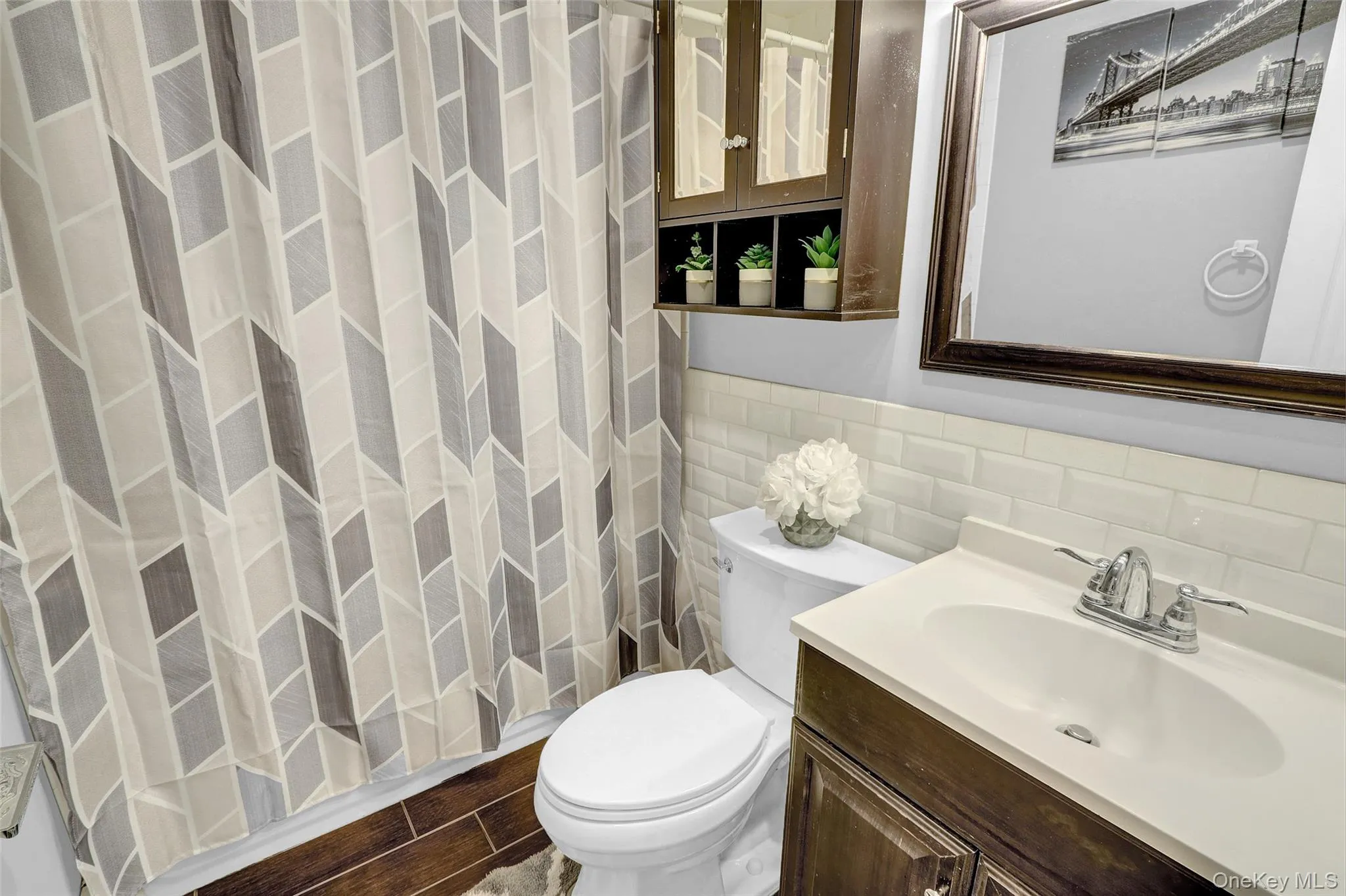 Bathroom featuring wood-finish flooring, a toilet, and a vanity with an integrated sink Bathroom featuring wood-finish flooring, a toilet, and a vanity with an integrated sink