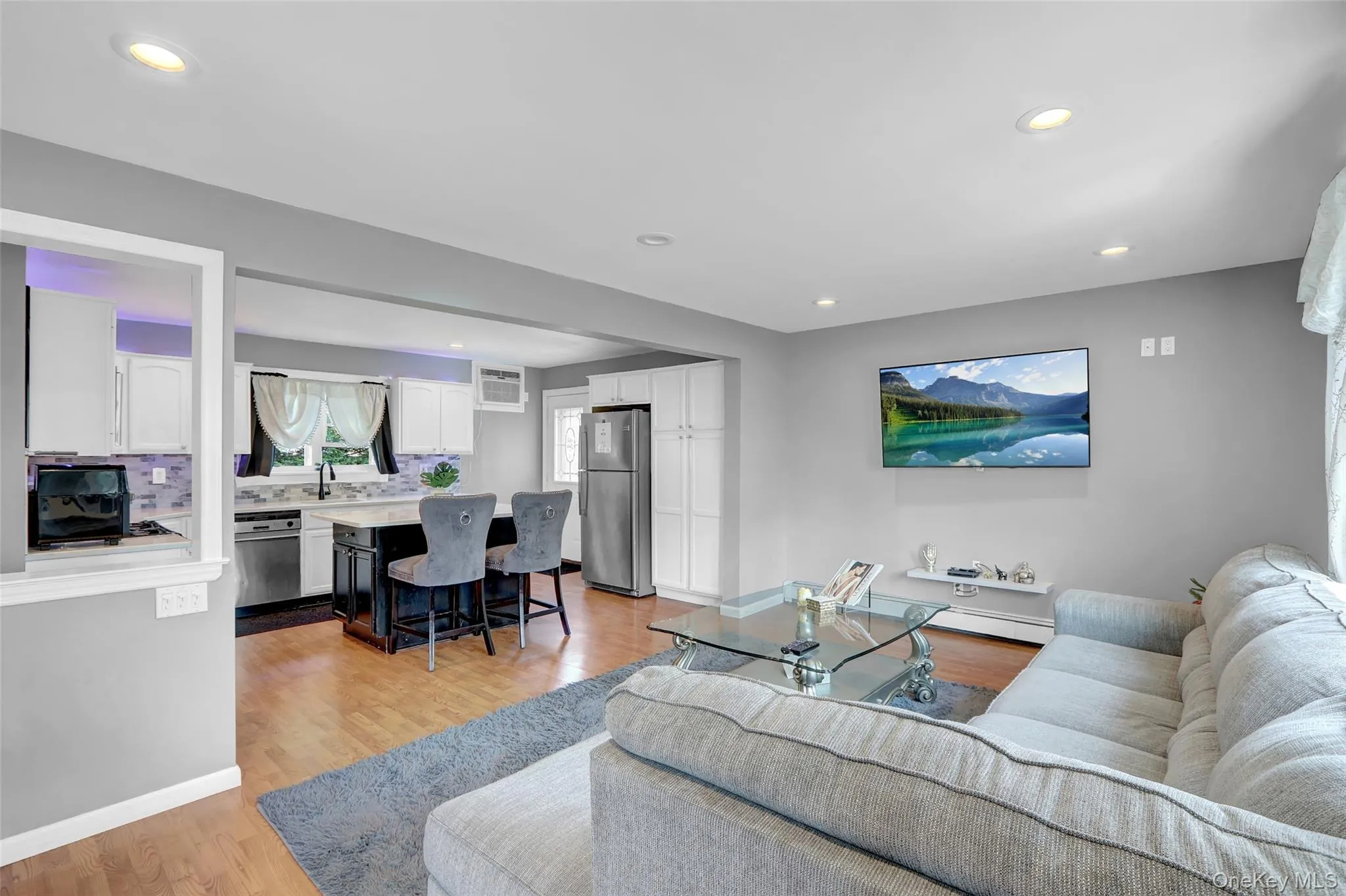 Open-concept living space with recessed lighting and wood-finish flooring Open-concept living space with recessed lighting and wood-finish flooring