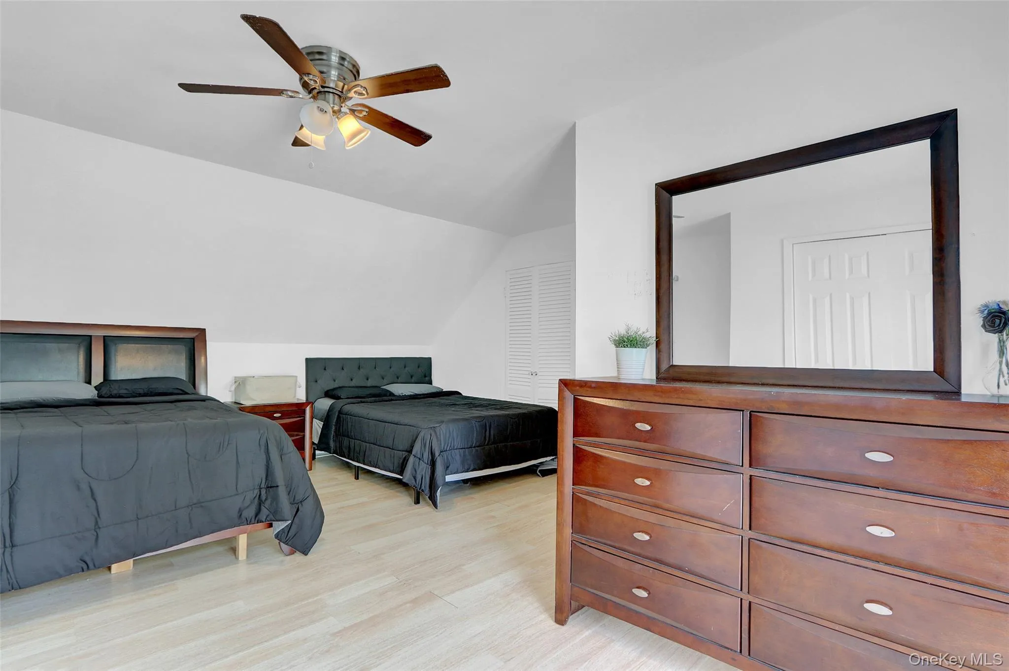 Spacious room featuring light wood-finish flooring, a ceiling fan with integrated lighting, and white walls Spacious room featuring light wood-finish flooring, a ceiling fan with integrated lighting, and white walls