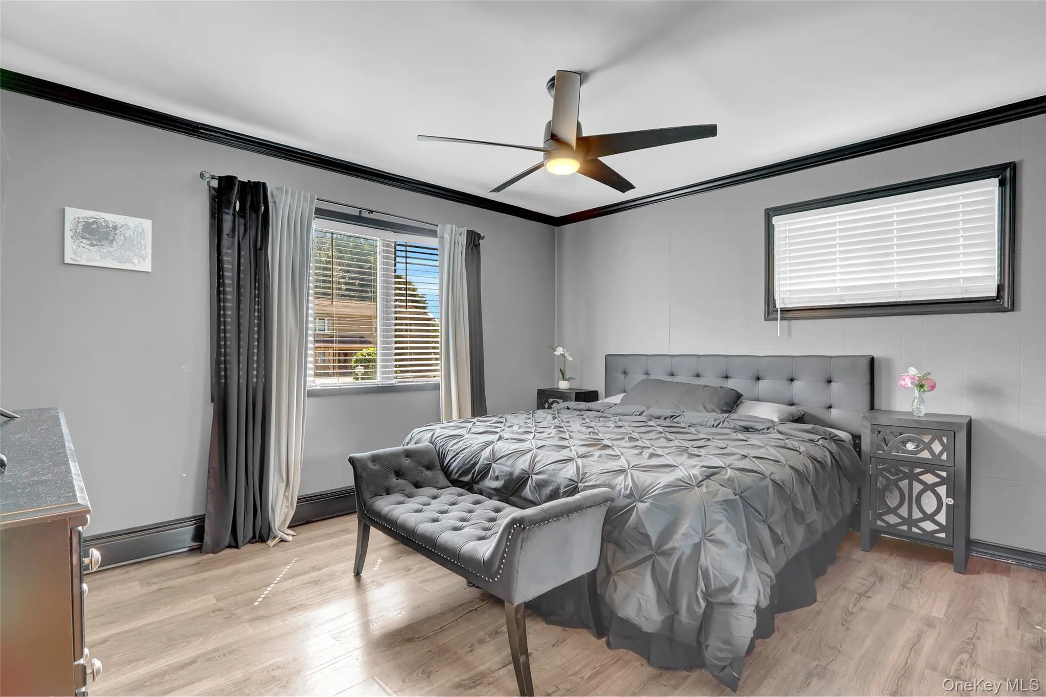 Spacious room featuring wood-finish flooring, light gray wall paint, and black crown molding Spacious room featuring wood-finish flooring, light gray wall paint, and black crown molding