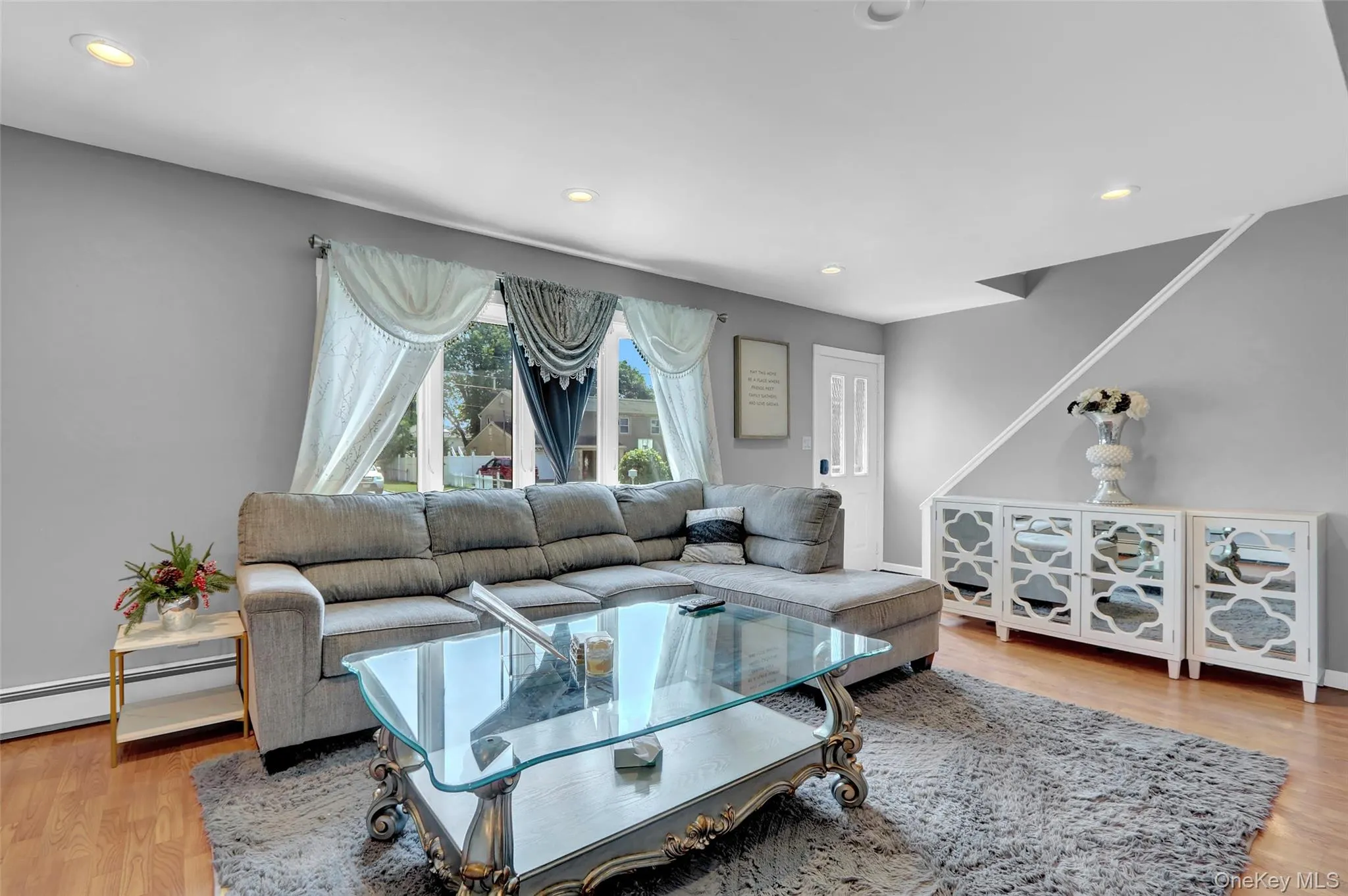 Spacious living area featuring wood-finish flooring, recessed lighting, and large windows Spacious living area featuring wood-finish flooring, recessed lighting, and large windows