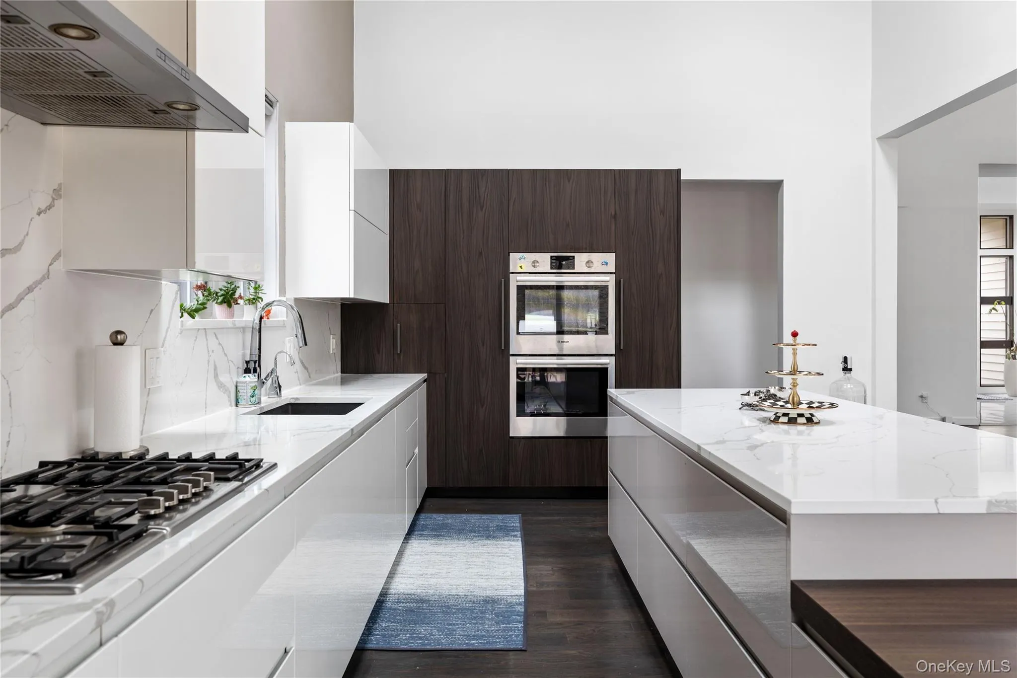 Contemporary kitchen featuring a gas range, stainless steel double wall ovens, an undermount sink, and a large central island Contemporary kitchen featuring a gas range, stainless steel double wall ovens, an undermount sink, and a large central island