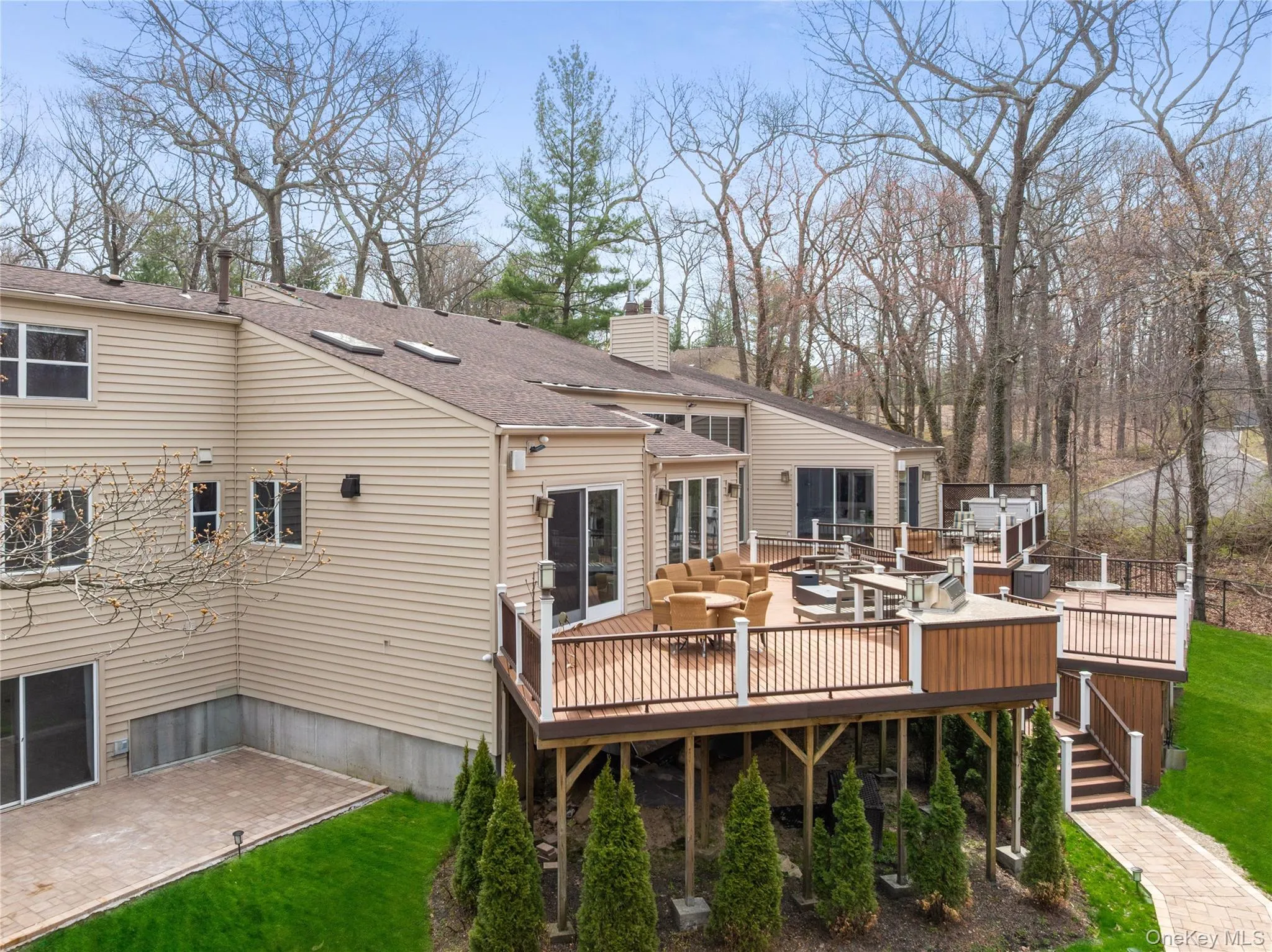 Multi-level rear decking with integrated outdoor kitchen, hot tub, and wood railing Multi-level rear decking with integrated outdoor kitchen, hot tub, and wood railing