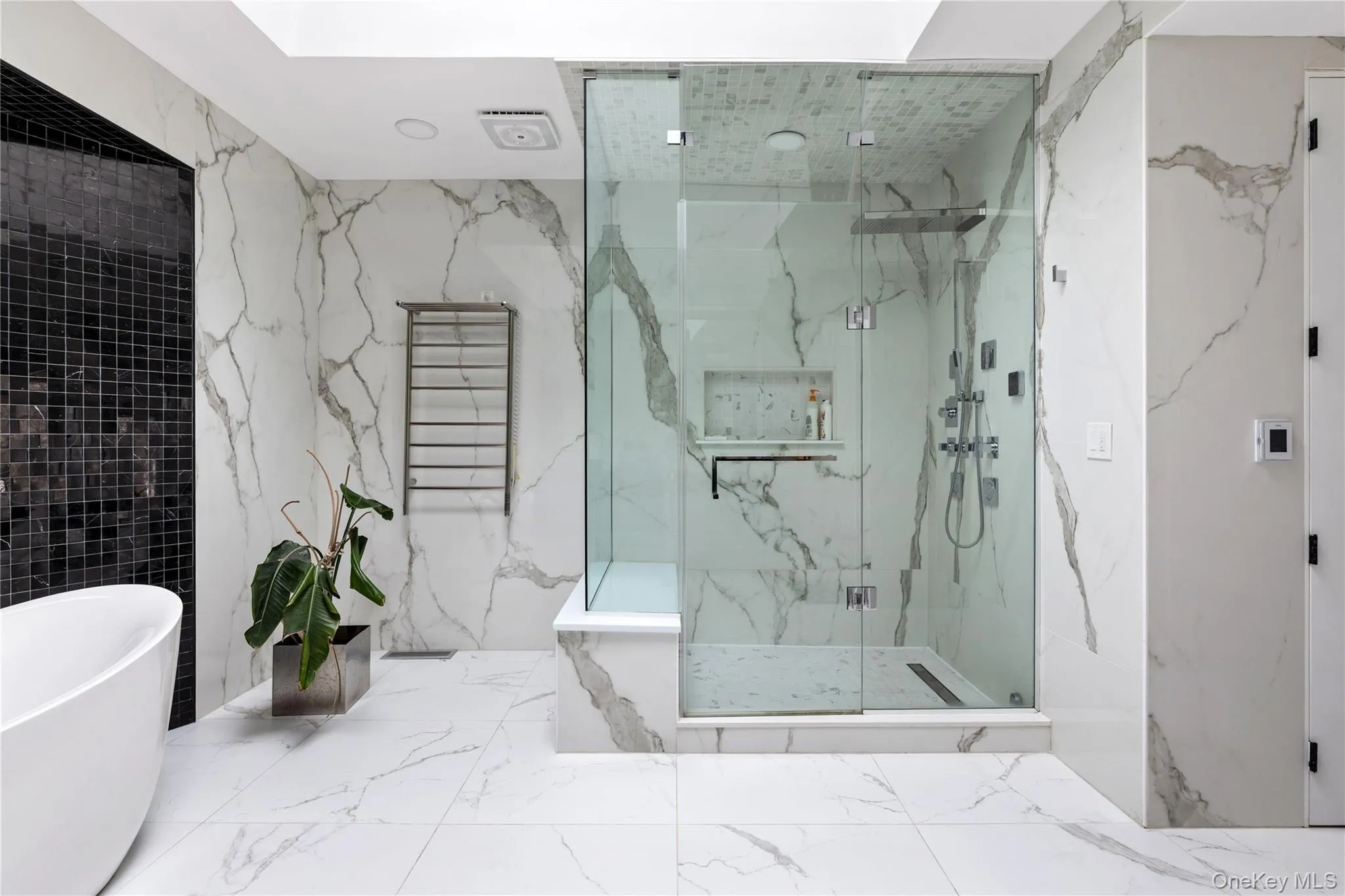 Spacious bathroom featuring large format marble-look tile flooring and wall finishes Spacious bathroom featuring large format marble-look tile flooring and wall finishes