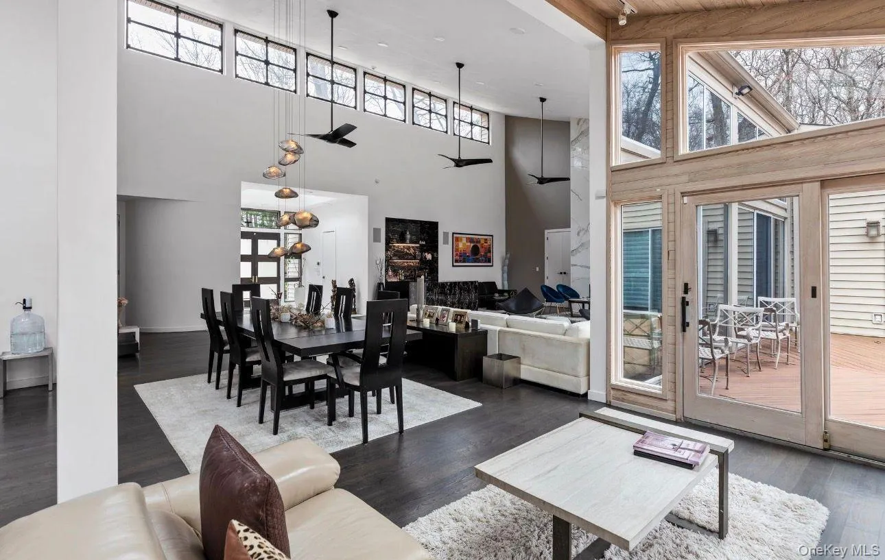 Expansive open-concept interior featuring high ceilings, dark wood-finish flooring, and multiple large windows Expansive open-concept interior featuring high ceilings, dark wood-finish flooring, and multiple large windows