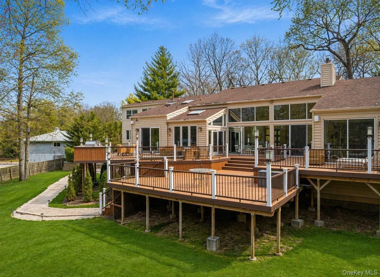 Multi-level outdoor deck featuring a hot tub, glass panel railings, and direct access to the interior through multiple sliding glass doors Multi-level outdoor deck featuring a hot tub, glass panel railings, and direct access to the interior through multiple sliding glass doors