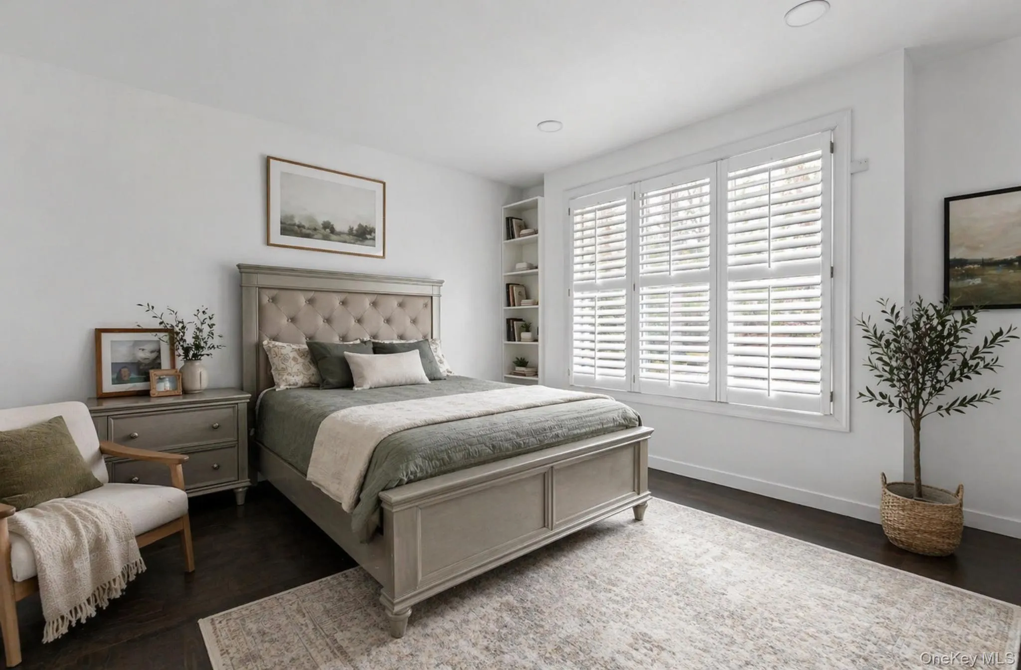 Spacious room featuring dark wood-finish flooring, recessed lighting, built-in shelving, and white plantation shutters on a large window Spacious room featuring dark wood-finish flooring, recessed lighting, built-in shelving, and white plantation shutters on a large window
