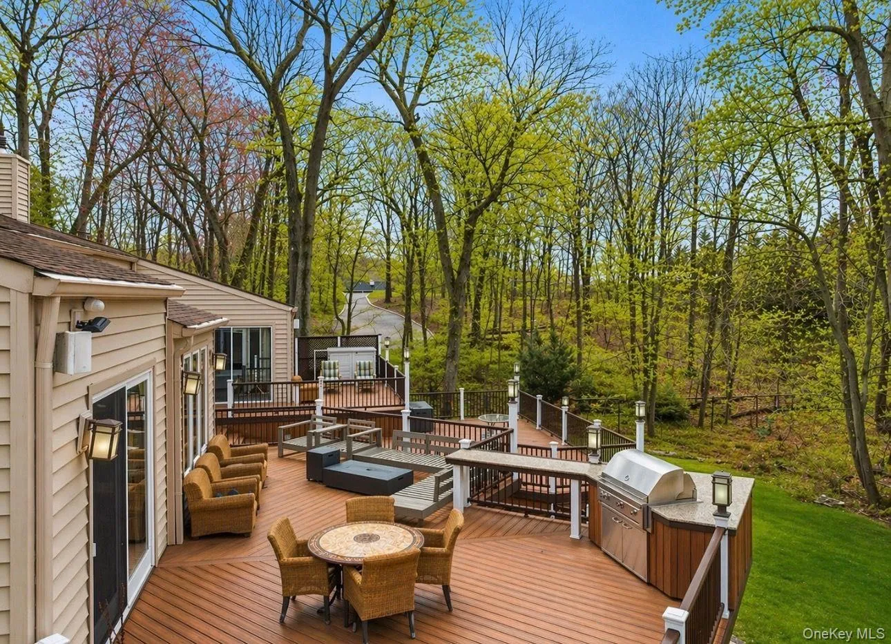 Expansive multi-level wood-finish deck with built-in outdoor kitchen, integrated lighting, and direct access from the home Expansive multi-level wood-finish deck with built-in outdoor kitchen, integrated lighting, and direct access from the home