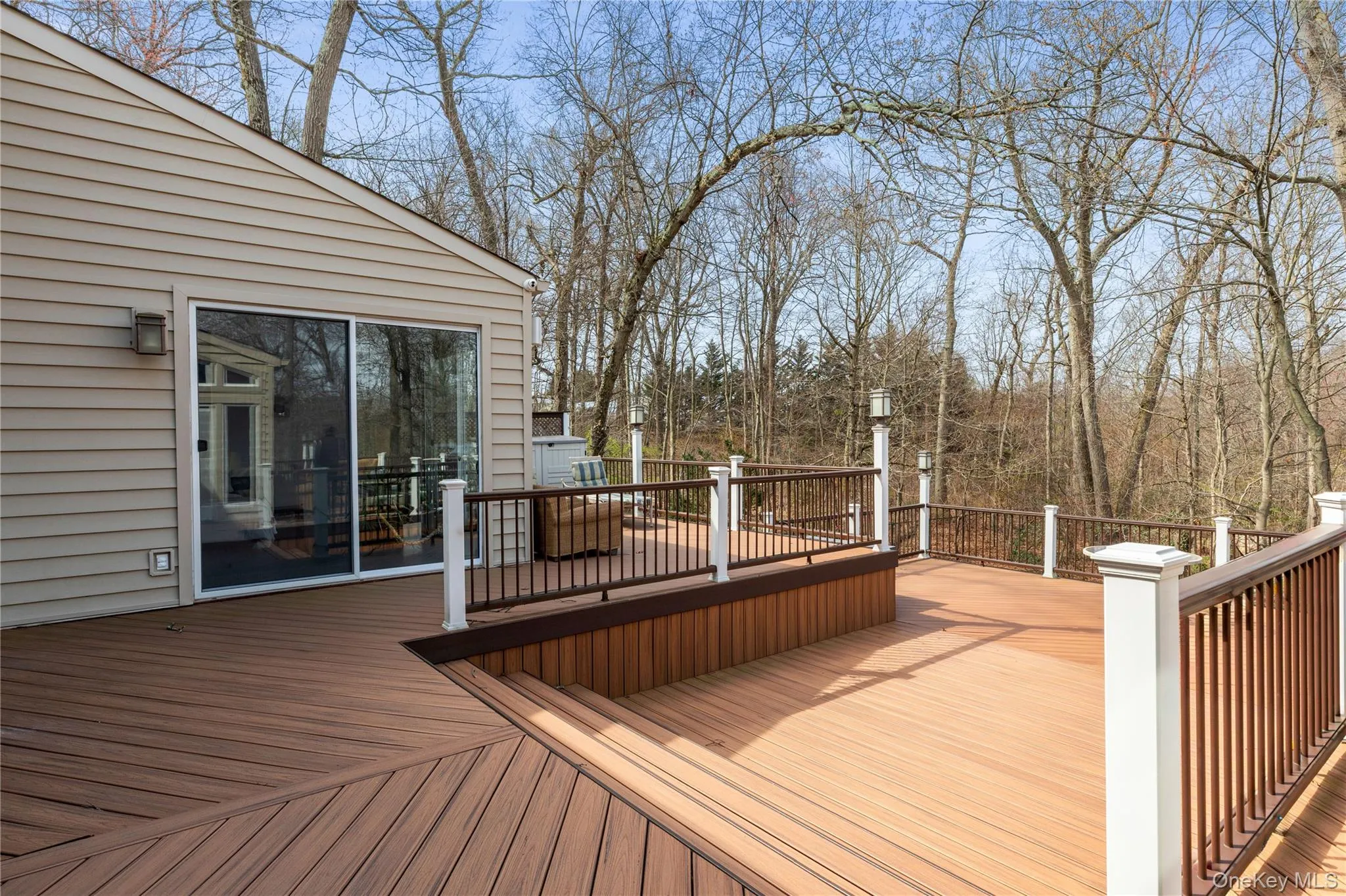 Multi-level composite deck with dark brown railing and white posts Multi-level composite deck with dark brown railing and white posts