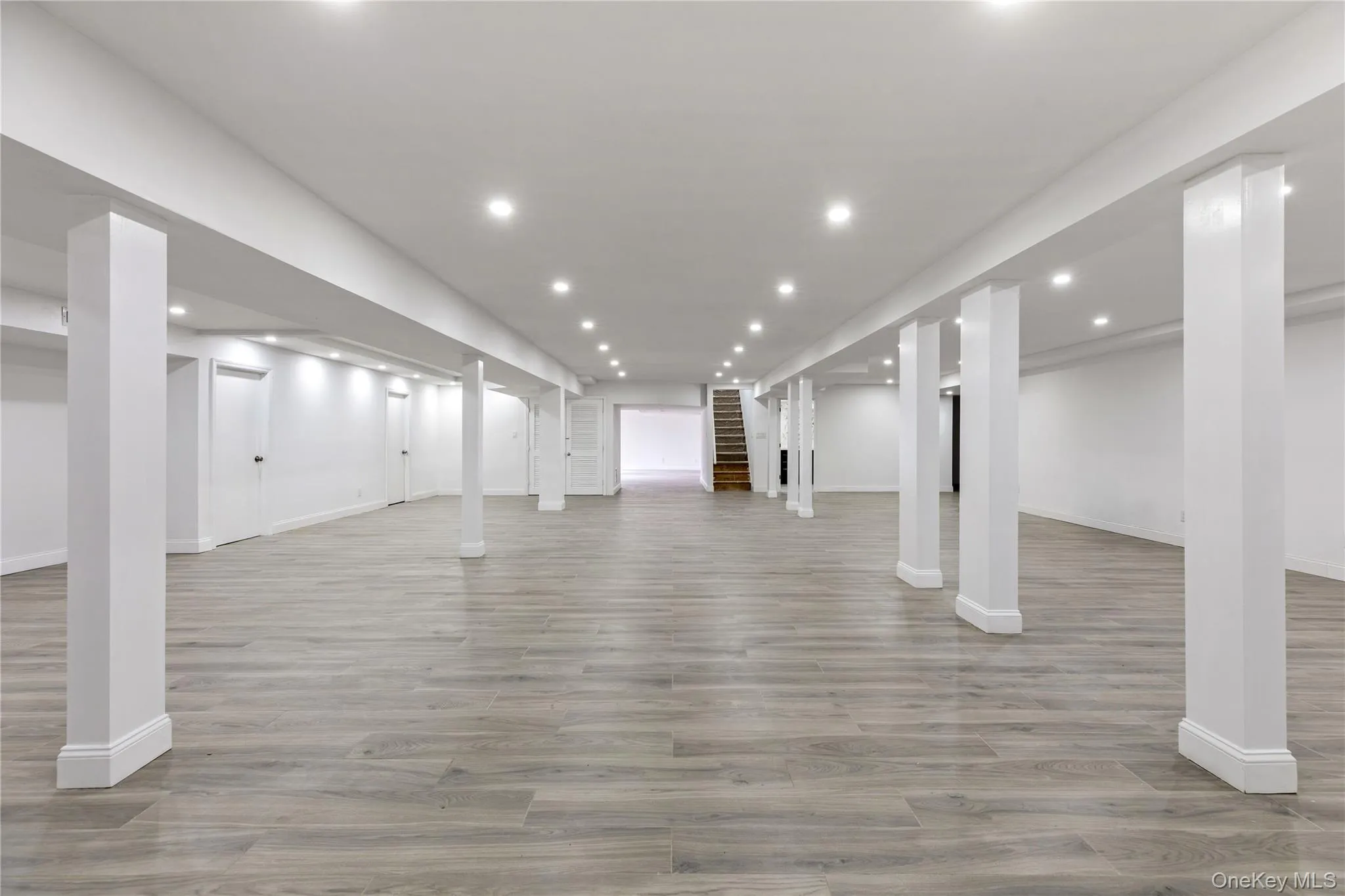 Expansive finished lower level featuring recessed lighting, wood-finish flooring, white painted support columns, and white walls Expansive finished lower level featuring recessed lighting, wood-finish flooring, white painted support columns, and white walls