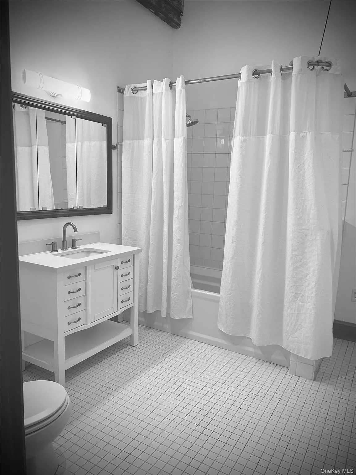 Full bathroom featuring shower / tub combo with curtain, vanity, tile patterned floors, and toilet Full bathroom featuring shower / tub combo with curtain, vanity, tile patterned floors, and toilet