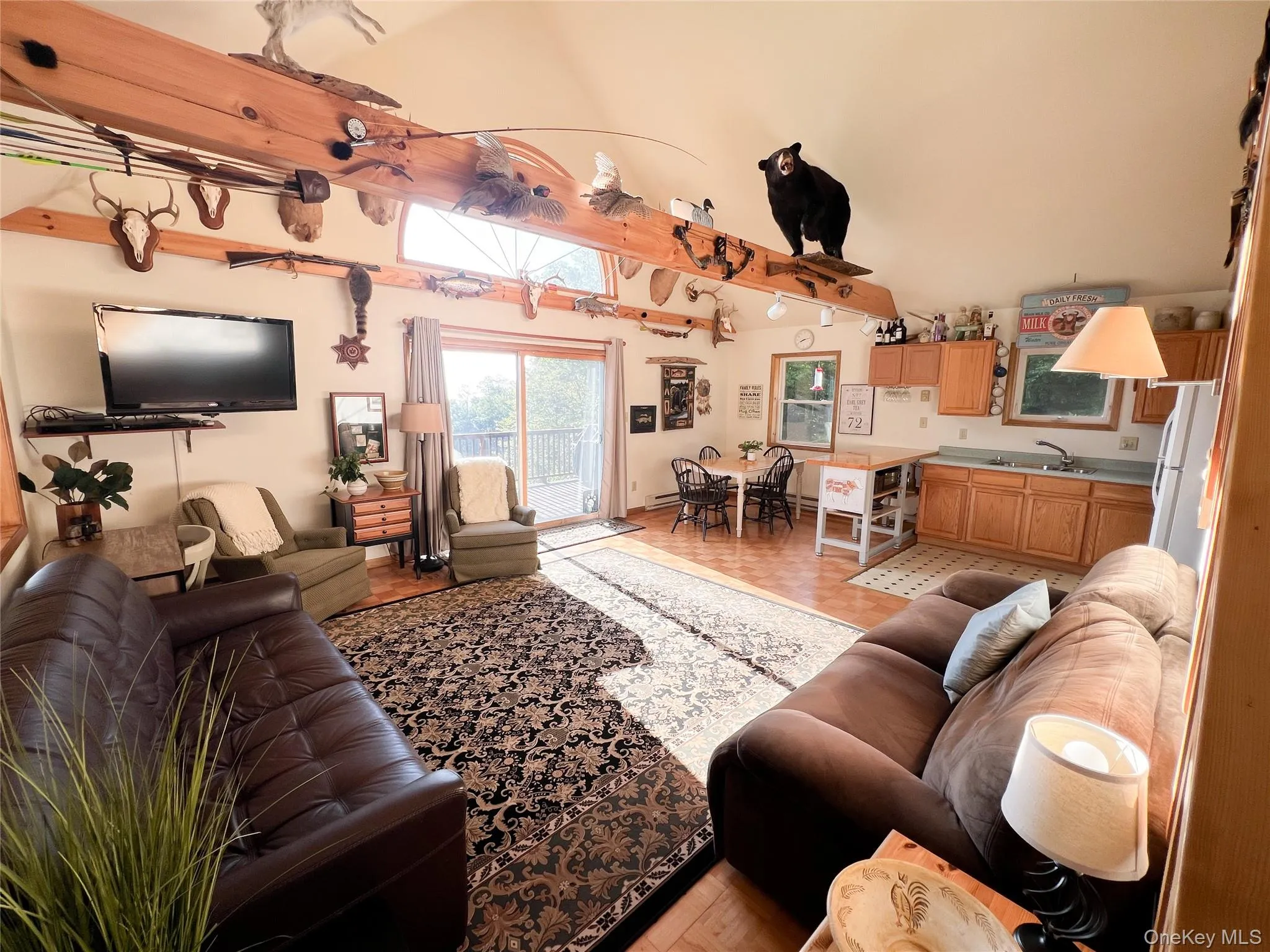 Open-concept living area featuring vaulted ceilings with exposed wood beams Open-concept living area featuring vaulted ceilings with exposed wood beams