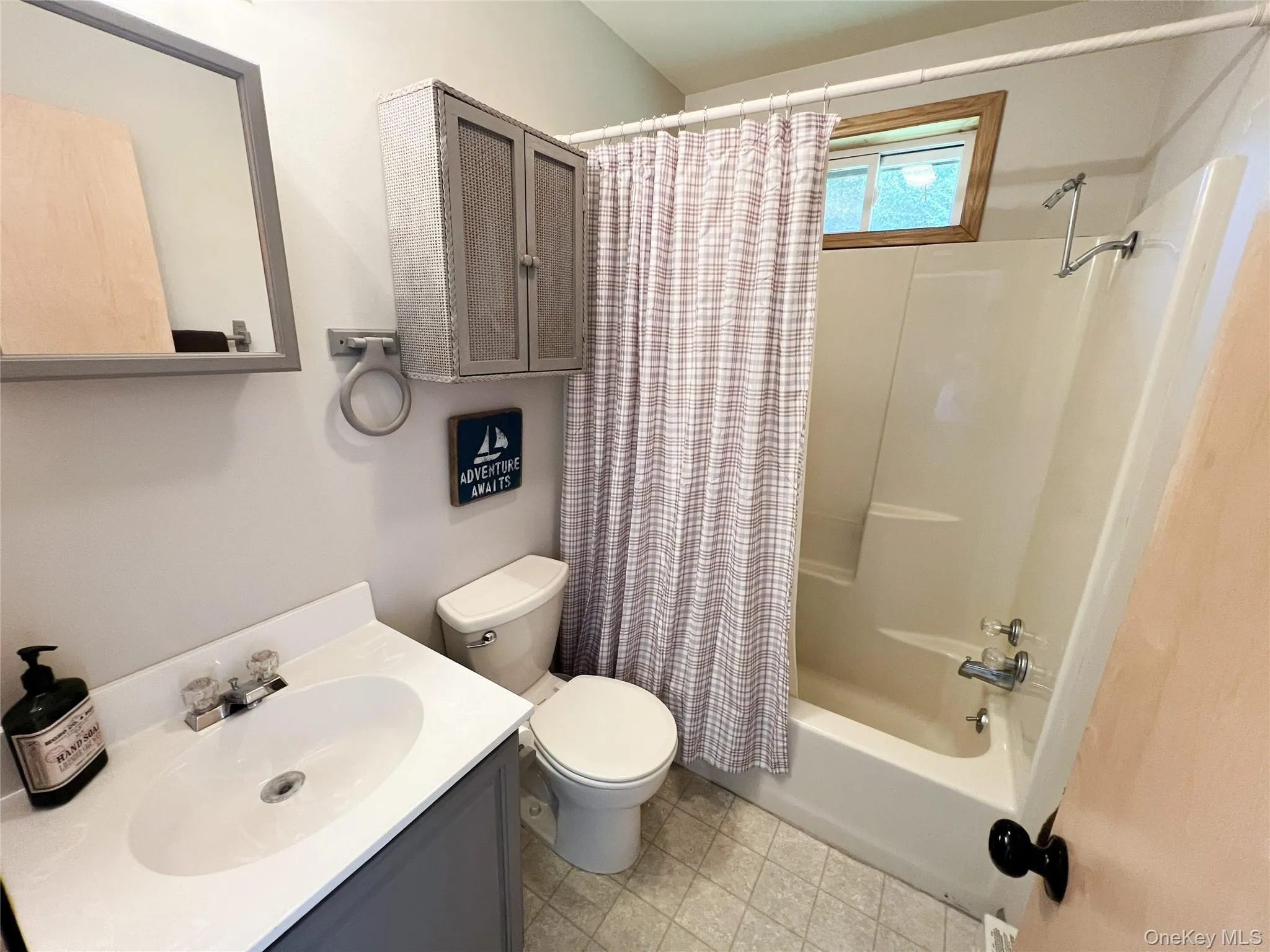 Bathroom featuring a single vanity with a white countertop and integrated sink, a built-in shower-tub combination, and tiled flooring Bathroom featuring a single vanity with a white countertop and integrated sink, a built-in shower-tub combination, and tiled flooring
