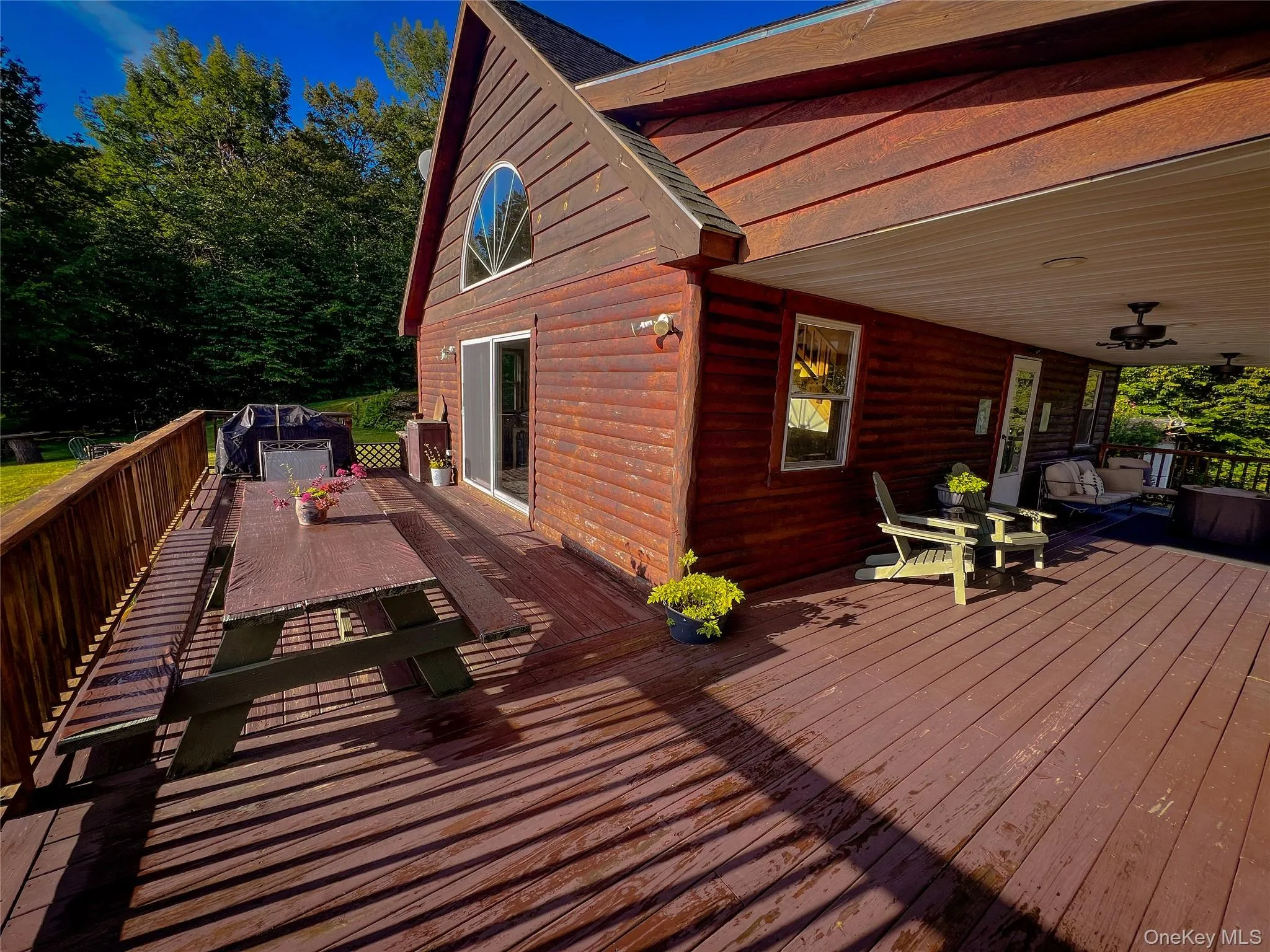 Expansive wood-finish deck with a rustic railing and a covered porch area Expansive wood-finish deck with a rustic railing and a covered porch area