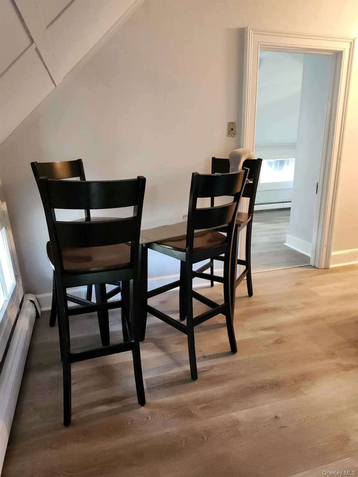 Dining space with baseboard heating, vaulted ceiling, and light wood-type flooring Dining space with baseboard heating, vaulted ceiling, and light wood-type flooring