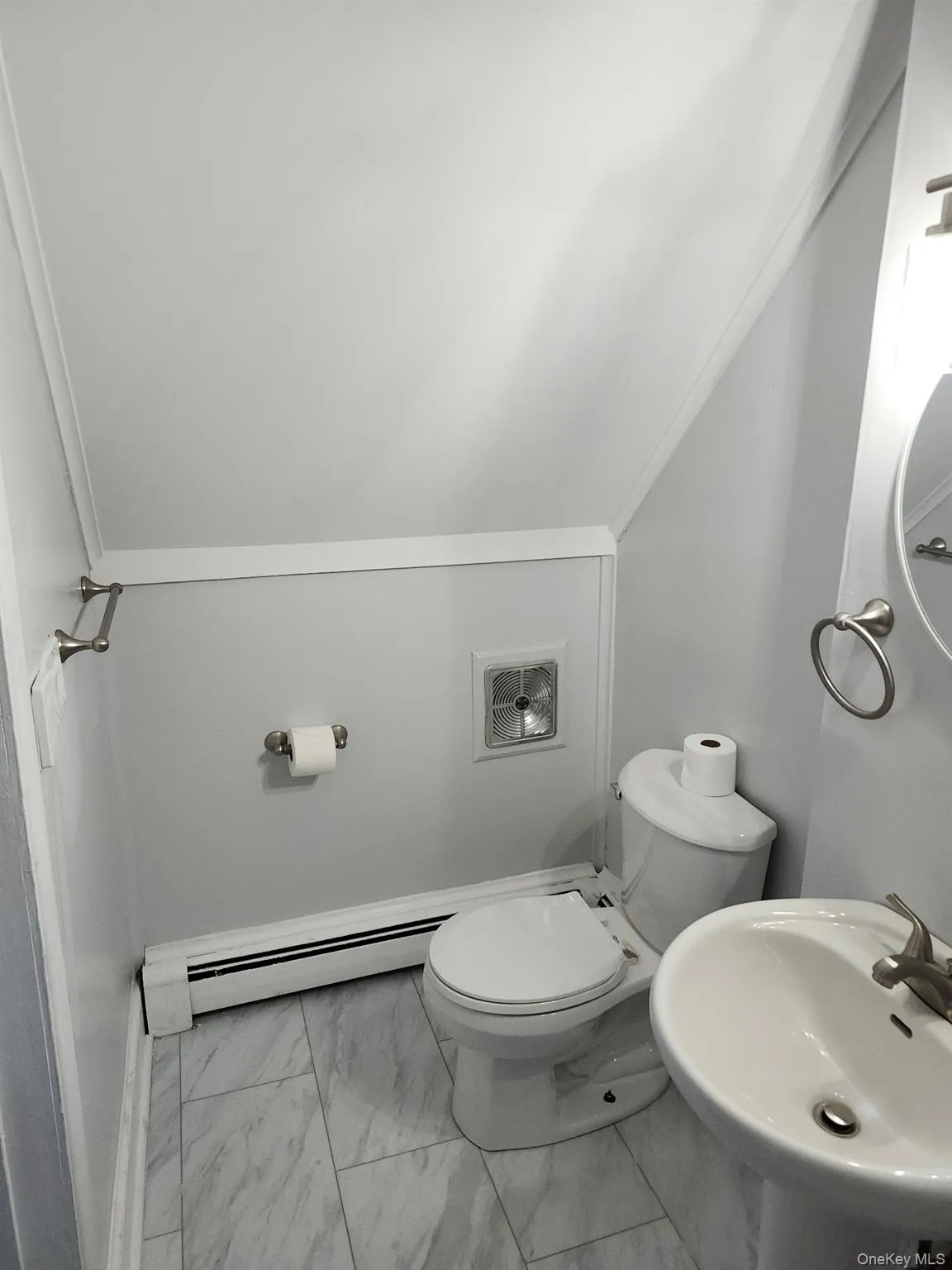 Bathroom with a baseboard radiator, lofted ceiling, toilet, and sink Bathroom with a baseboard radiator, lofted ceiling, toilet, and sink