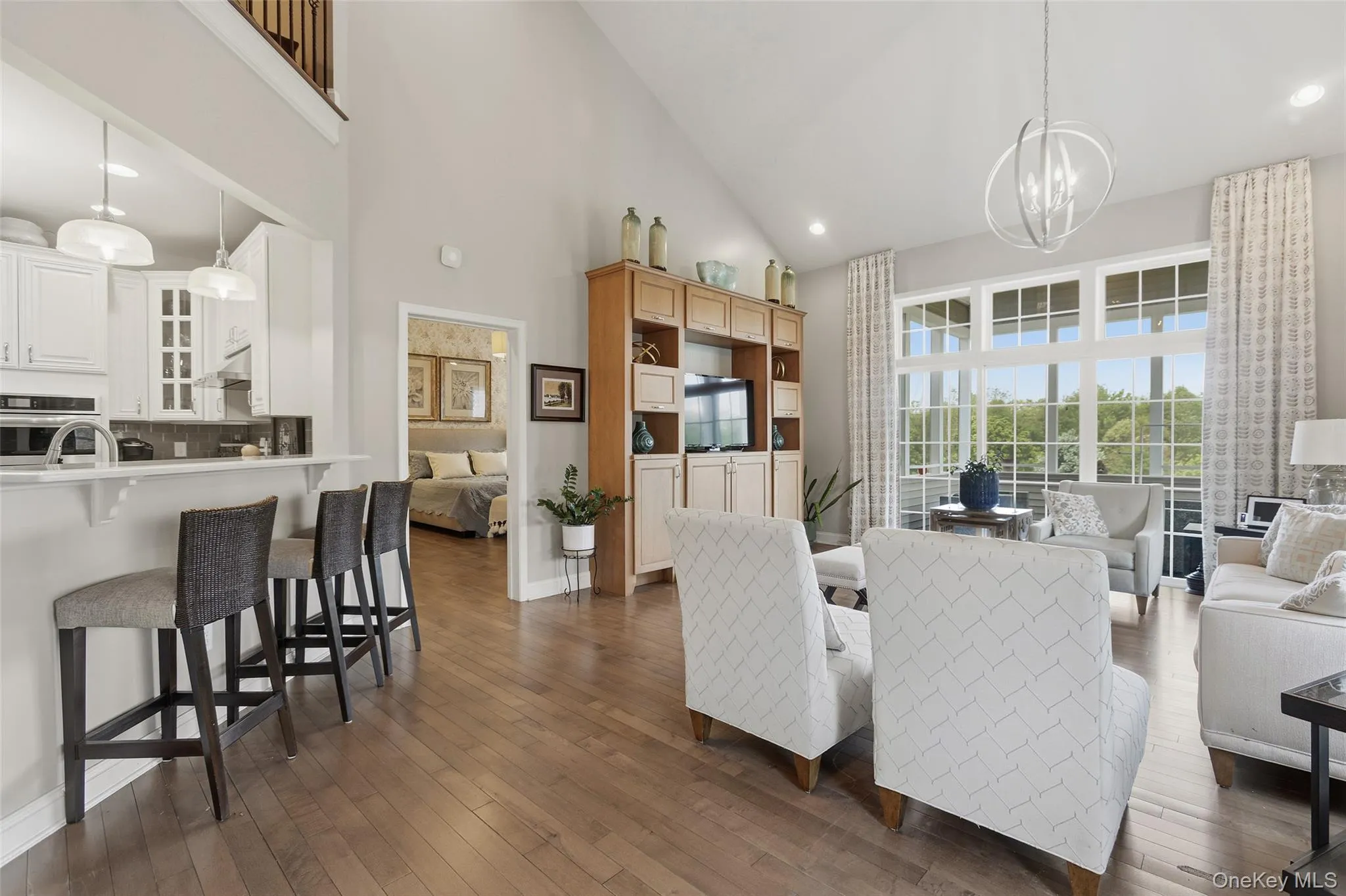 Spacious living area featuring high vaulted ceilings, expansive windows, wood-finish flooring, and a built-in media center Spacious living area featuring high vaulted ceilings, expansive windows, wood-finish flooring, and a built-in media center