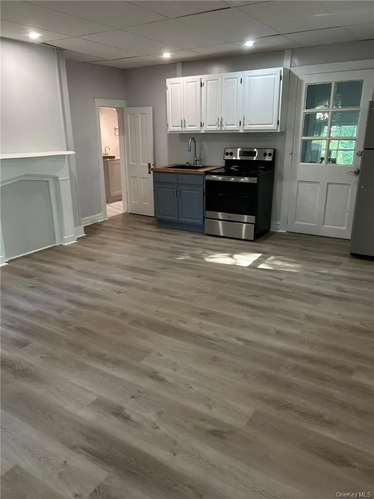 Kitchen featuring stainless steel appliances, white cabinets, hardwood / wood-style flooring, and sink Kitchen featuring stainless steel appliances, white cabinets, hardwood / wood-style flooring, and sink