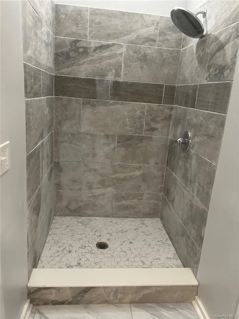 Bathroom with tiled shower and tile flooring Bathroom with tiled shower and tile flooring