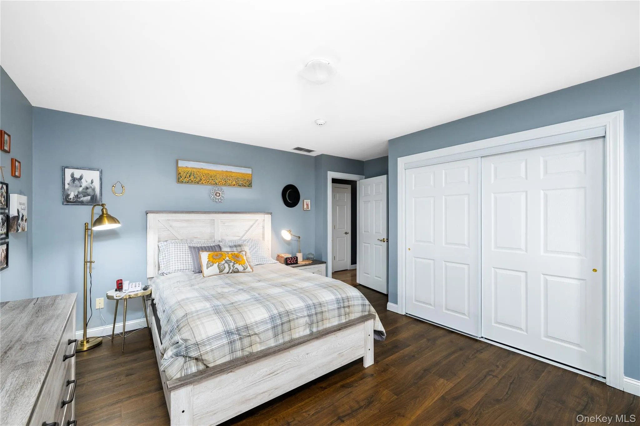 Spacious room featuring wood-finish flooring, light blue walls, and a white ceiling Spacious room featuring wood-finish flooring, light blue walls, and a white ceiling