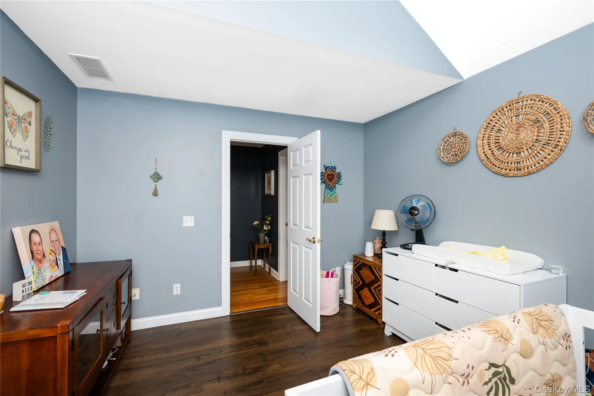 Room featuring vaulted ceiling, dark wood-finish flooring, and a white interior door Room featuring vaulted ceiling, dark wood-finish flooring, and a white interior door