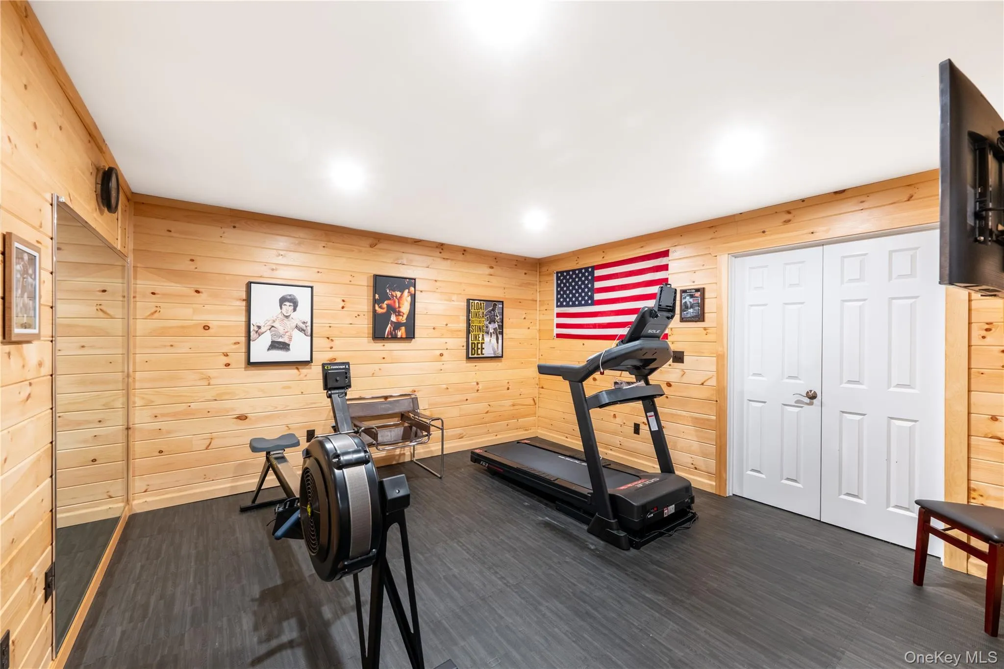 Room with pine wood-finish paneling, dark rubber flooring, and recessed ceiling lighting Room with pine wood-finish paneling, dark rubber flooring, and recessed ceiling lighting