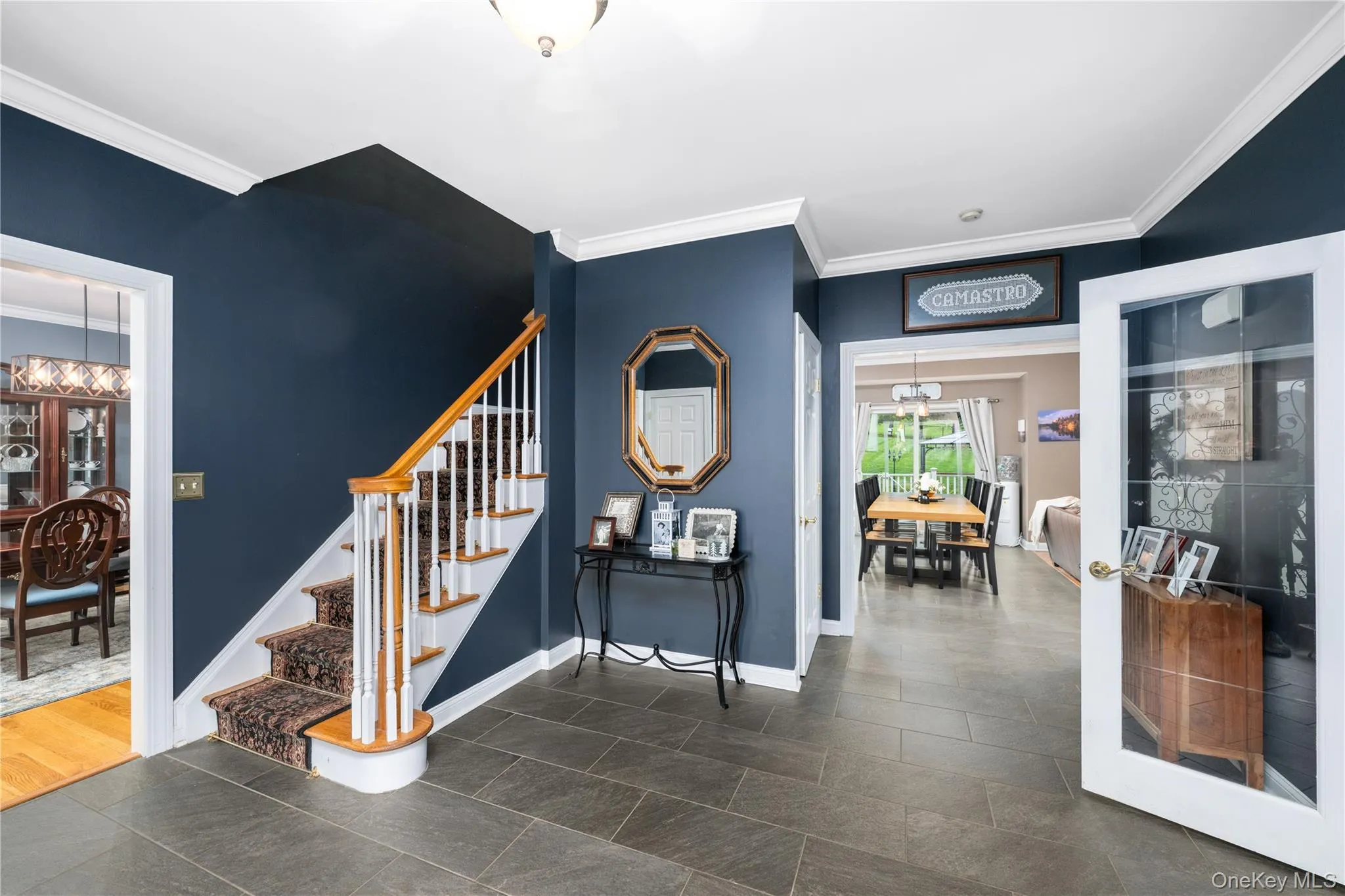 Foyer featuring slate-style flooring, a staircase with white risers and wood-finish handrails, deep blue walls, crown molding, and recessed lighting Foyer featuring slate-style flooring, a staircase with white risers and wood-finish handrails, deep blue walls, crown molding, and recessed lighting