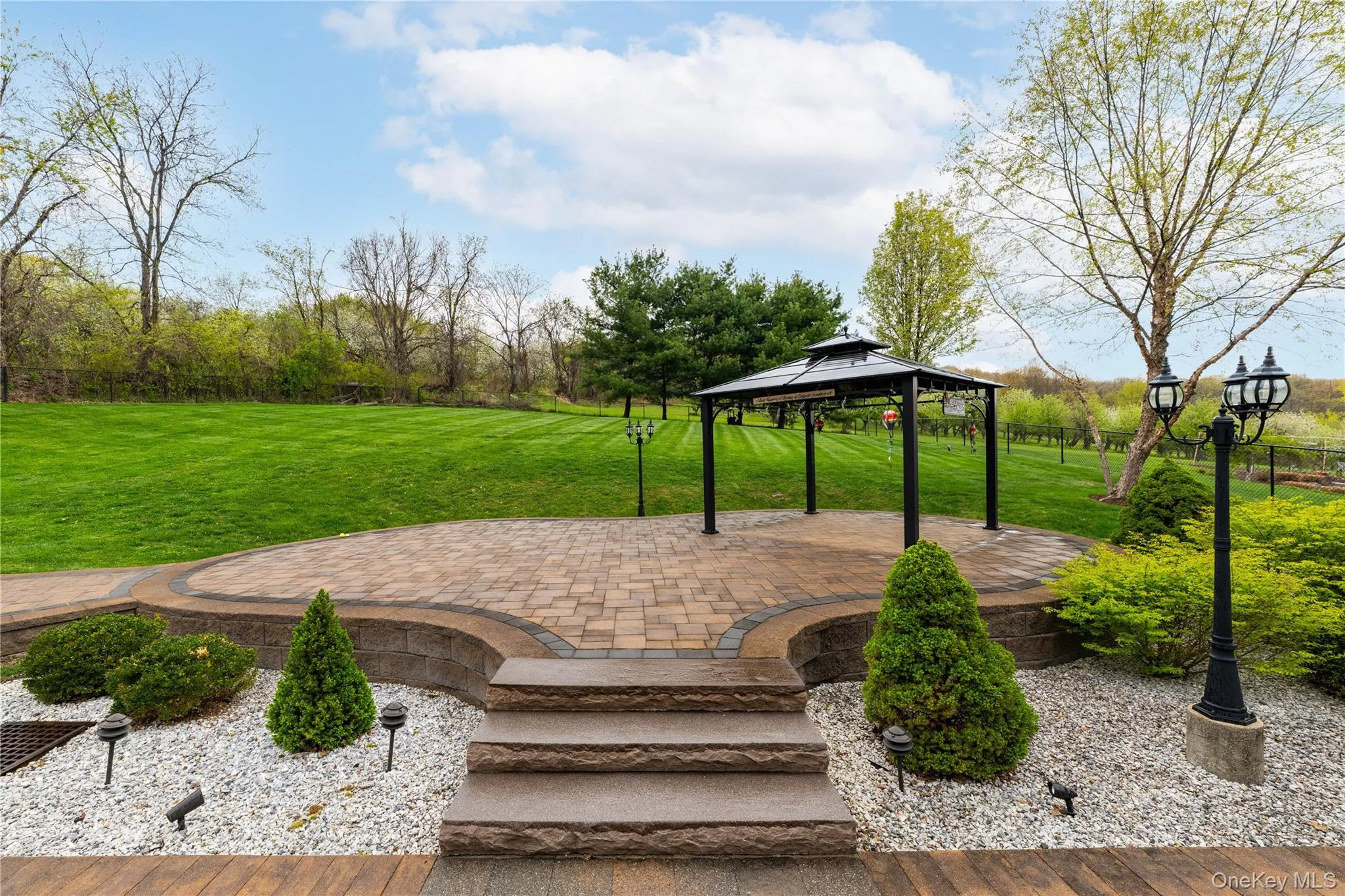 Raised paver patio with gazebo surrounded by mature landscaping Raised paver patio with gazebo surrounded by mature landscaping