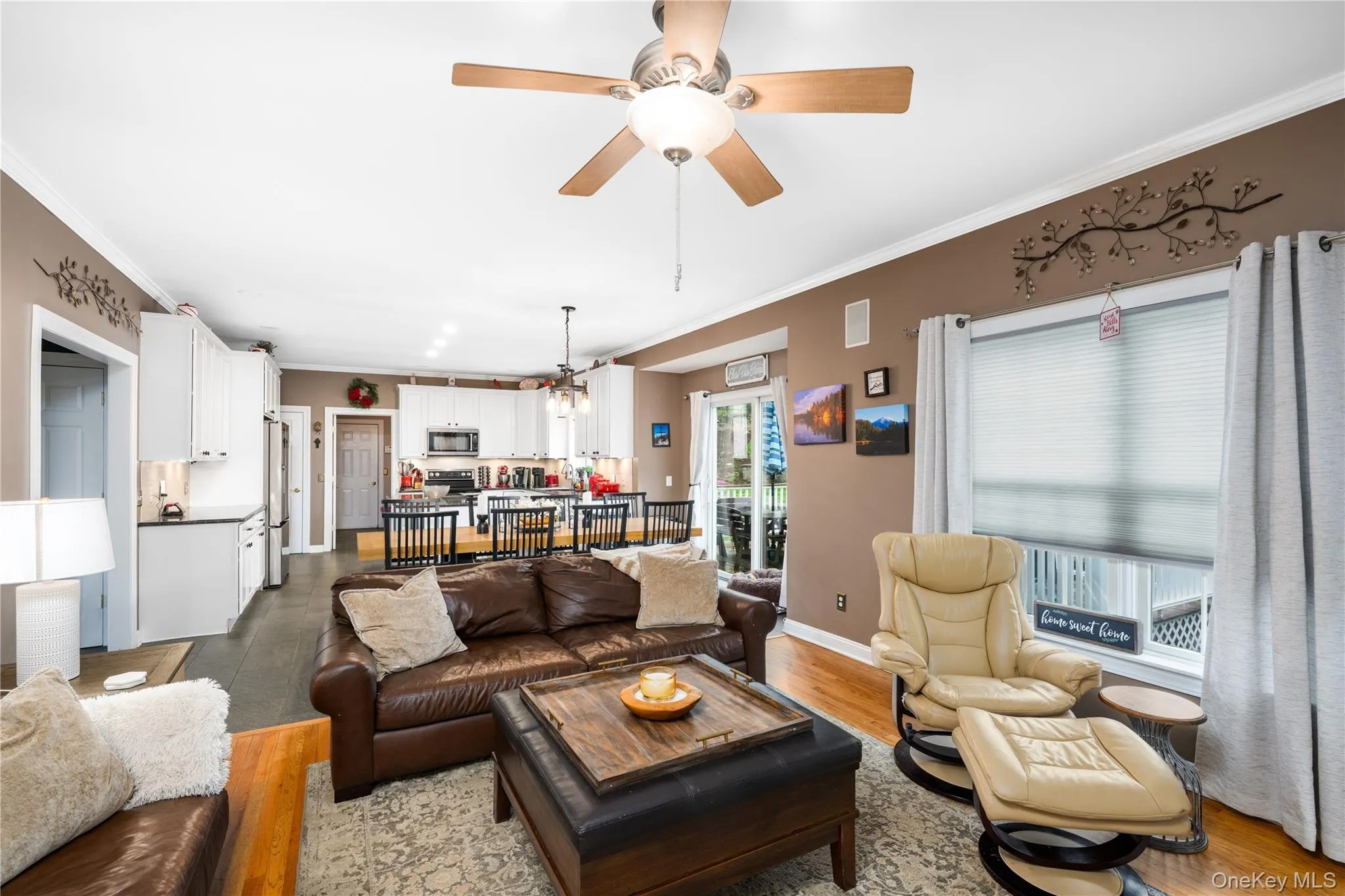 Open-concept living area with wood-finish flooring, crown molding, a ceiling fan, and recessed lighting Open-concept living area with wood-finish flooring, crown molding, a ceiling fan, and recessed lighting