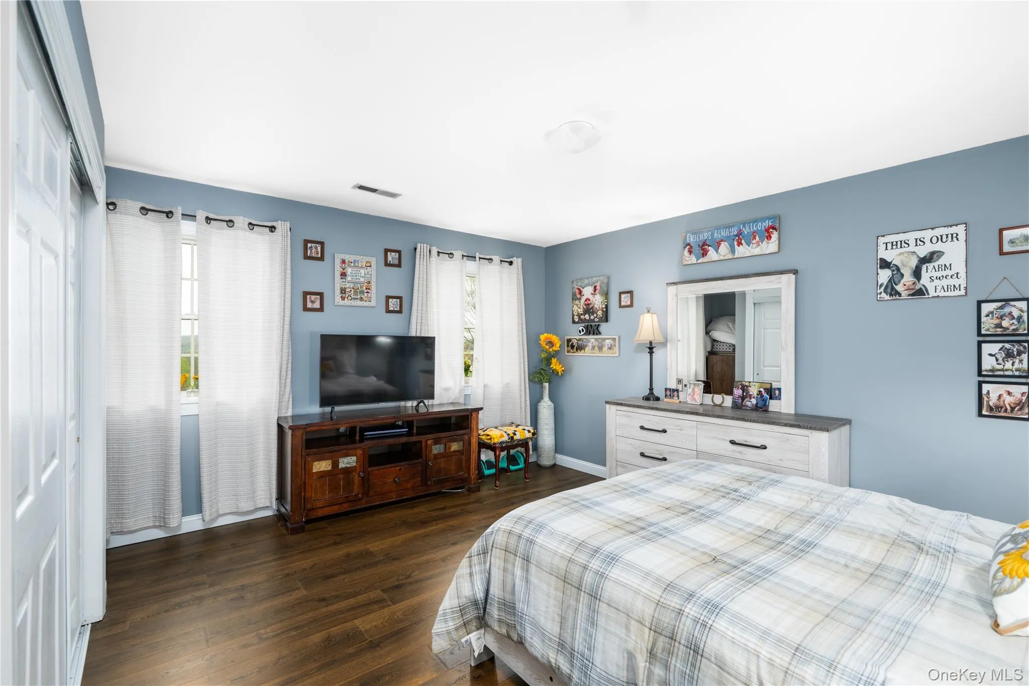 Spacious room featuring wood-finish flooring, light blue walls, and white trim Spacious room featuring wood-finish flooring, light blue walls, and white trim