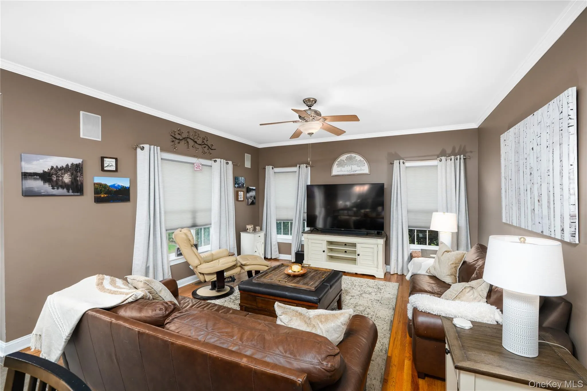 Spacious living area featuring warm neutral wall tones and crown molding Spacious living area featuring warm neutral wall tones and crown molding