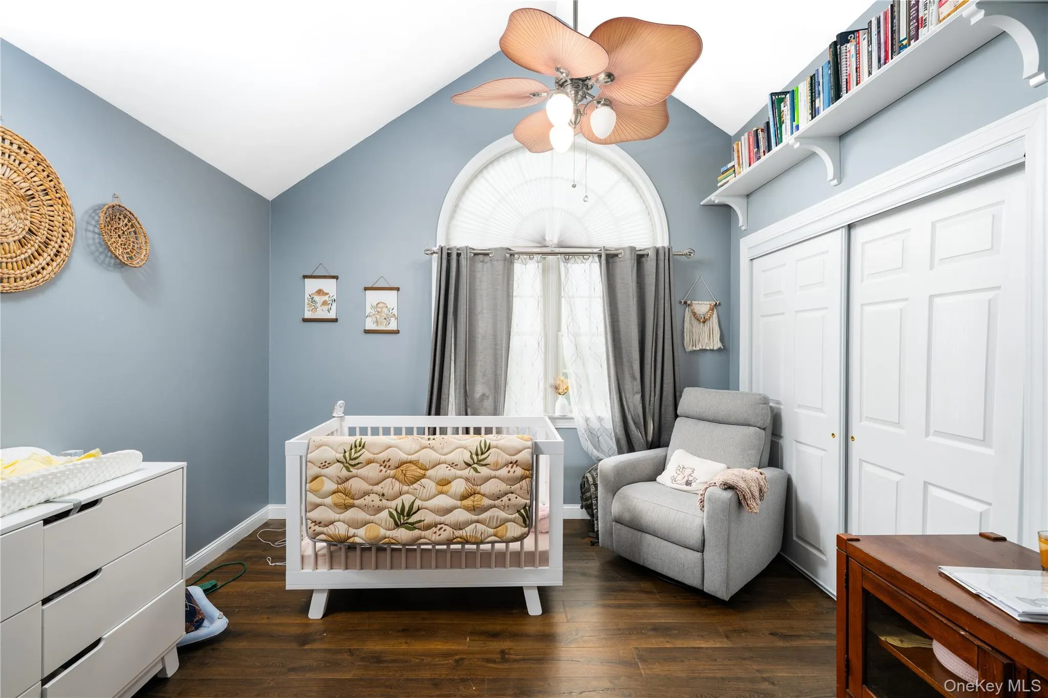 Vaulted ceiling room featuring wood-finish flooring and an arched window with drapes Vaulted ceiling room featuring wood-finish flooring and an arched window with drapes