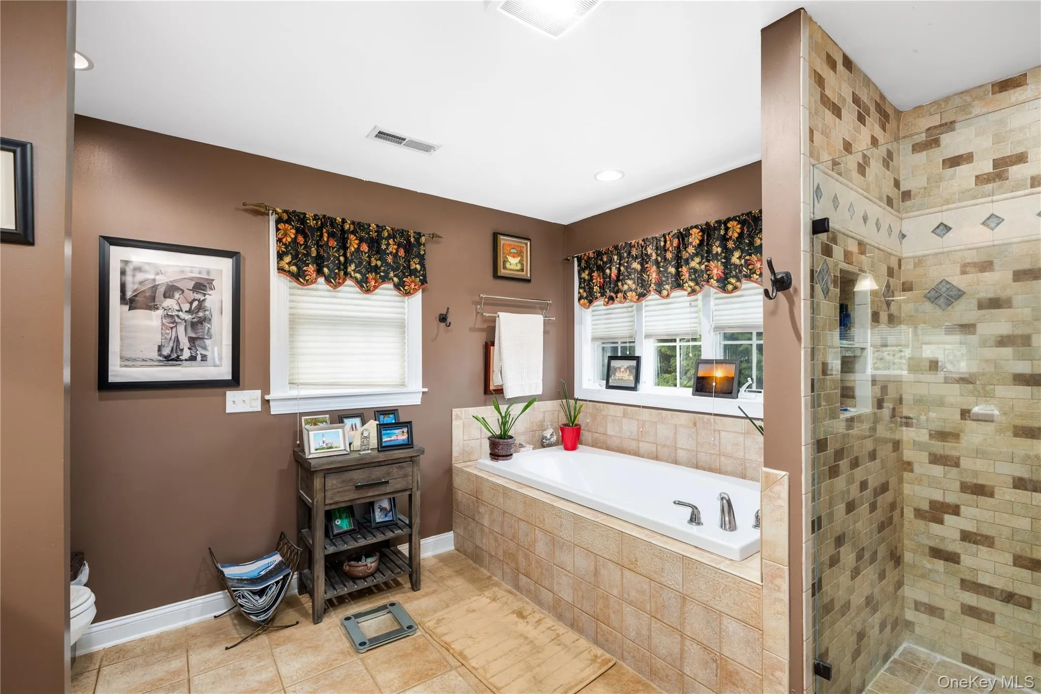 Bathroom featuring a built-in jetted soaker tub with tile surround, a glass-enclosed shower with tile work, recessed lighting, and a window with blinds Bathroom featuring a built-in jetted soaker tub with tile surround, a glass-enclosed shower with tile work, recessed lighting, and a window with blinds