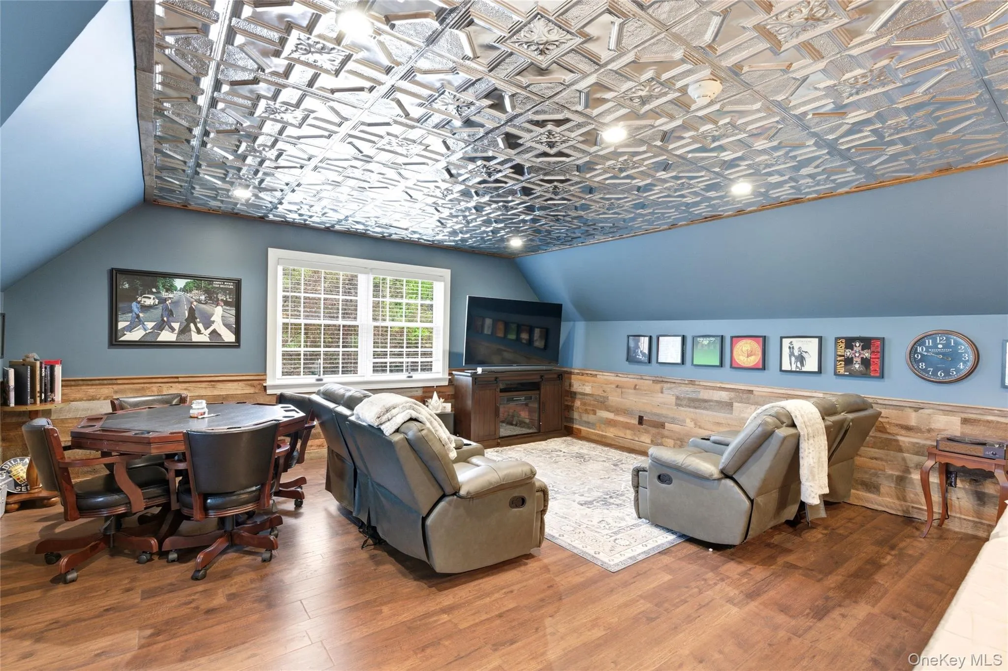 Recreation room featuring a distinctive tin ceiling with recessed lighting, wood-finish flooring, and shiplap wall accents Recreation room featuring a distinctive tin ceiling with recessed lighting, wood-finish flooring, and shiplap wall accents