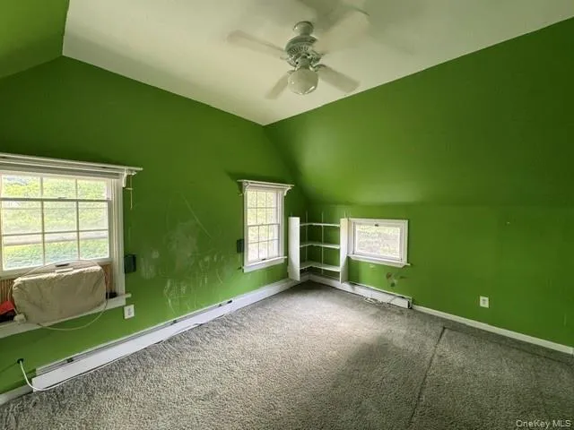 Room featuring a sloped ceiling, recessed window, built-in shelving, and a ceiling fan Room featuring a sloped ceiling, recessed window, built-in shelving, and a ceiling fan