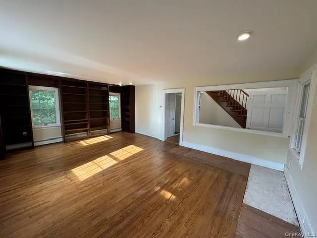 Spacious room featuring wood-finish flooring, recessed lighting, and built-in shelving Spacious room featuring wood-finish flooring, recessed lighting, and built-in shelving