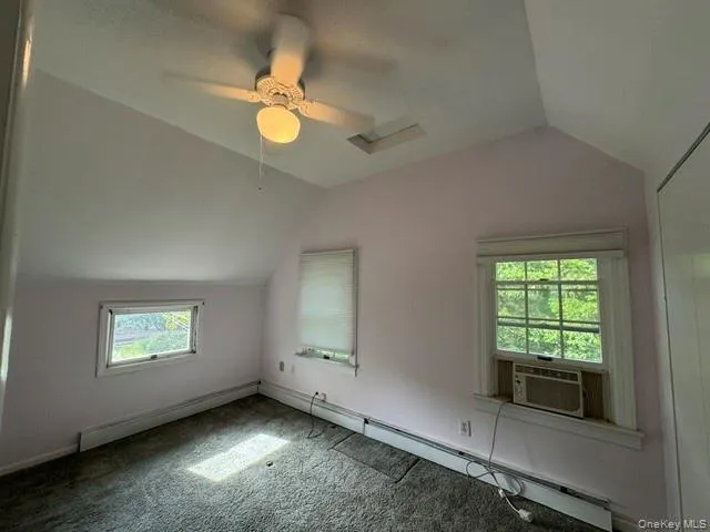 Room featuring a sloped ceiling, overhead ceiling fan with lighting, two windows, and wall-to-wall carpeting Room featuring a sloped ceiling, overhead ceiling fan with lighting, two windows, and wall-to-wall carpeting