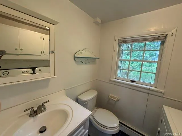 Bathroom featuring a vanity with an integrated sink, a medicine cabinet, and a window with natural light Bathroom featuring a vanity with an integrated sink, a medicine cabinet, and a window with natural light