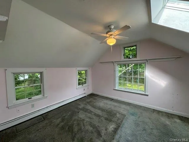 Attic space featuring sloped ceilings, multiple windows with white trim, and a skylight Attic space featuring sloped ceilings, multiple windows with white trim, and a skylight