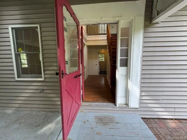 Red entry door with glass panels opening to an interior with wood-finish flooring Red entry door with glass panels opening to an interior with wood-finish flooring