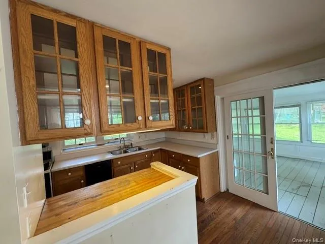 Kitchen featuring wood cabinetry with glass-front upper cabinets, a double basin sink, and a wood-finish breakfast bar Kitchen featuring wood cabinetry with glass-front upper cabinets, a double basin sink, and a wood-finish breakfast bar