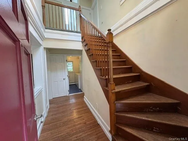 Entryway featuring wood-finish flooring, a grand staircase with wood balusters, and a second-story landing with an open railing Entryway featuring wood-finish flooring, a grand staircase with wood balusters, and a second-story landing with an open railing
