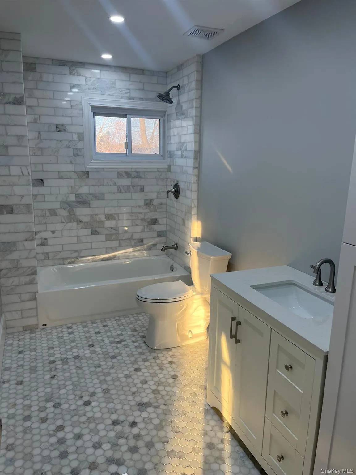 Full bathroom with tile patterned floors, toilet, vanity, and tiled shower / bath Full bathroom with tile patterned floors, toilet, vanity, and tiled shower / bath