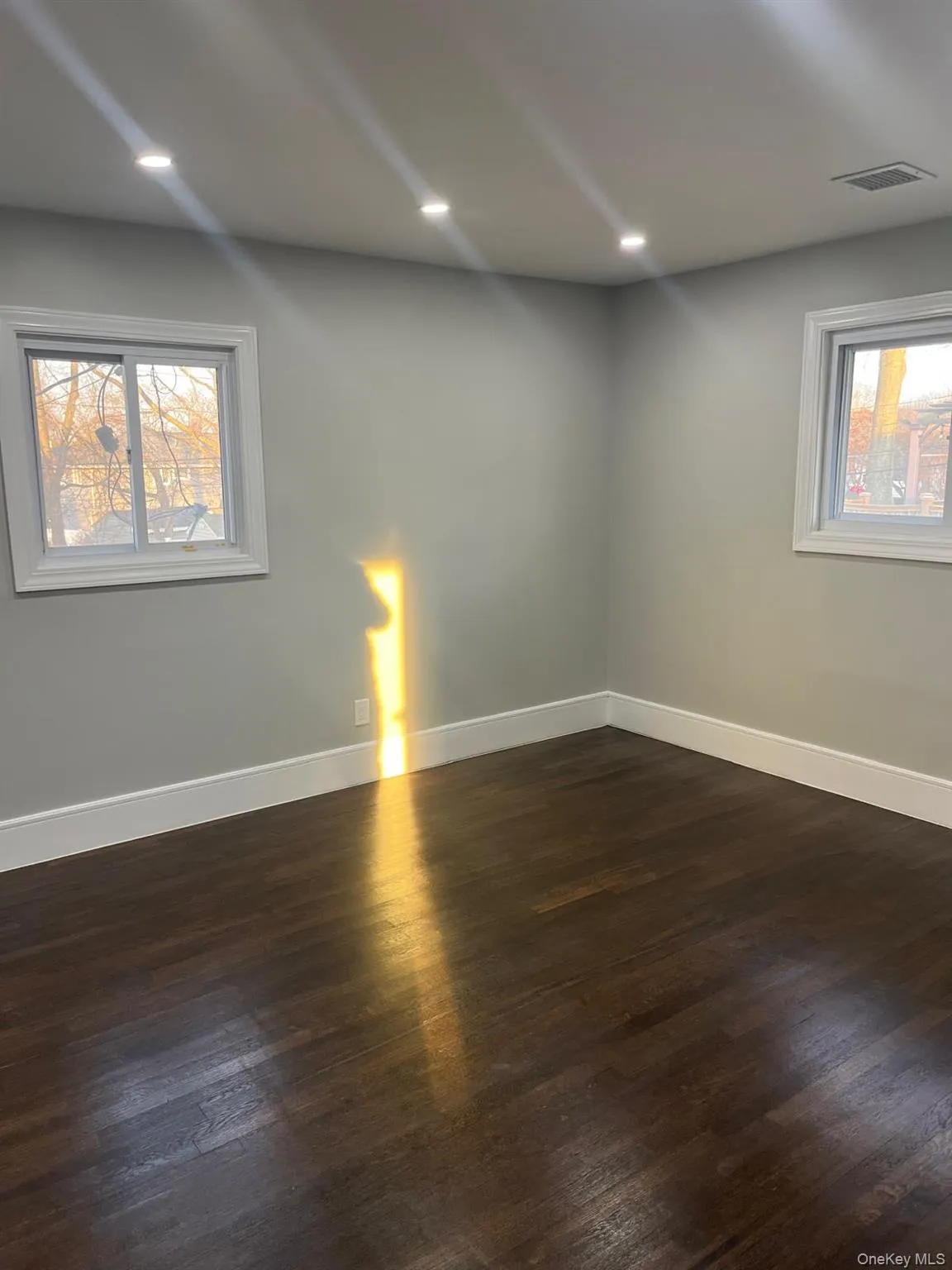 Unfurnished room with plenty of natural light and dark hardwood / wood-style floors Unfurnished room with plenty of natural light and dark hardwood / wood-style floors