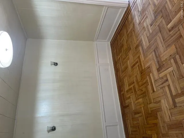Hardwood parquet flooring, decorative wainscoting, and a ceiling-mounted light fixture define this interior space Hardwood parquet flooring, decorative wainscoting, and a ceiling-mounted light fixture define this interior space