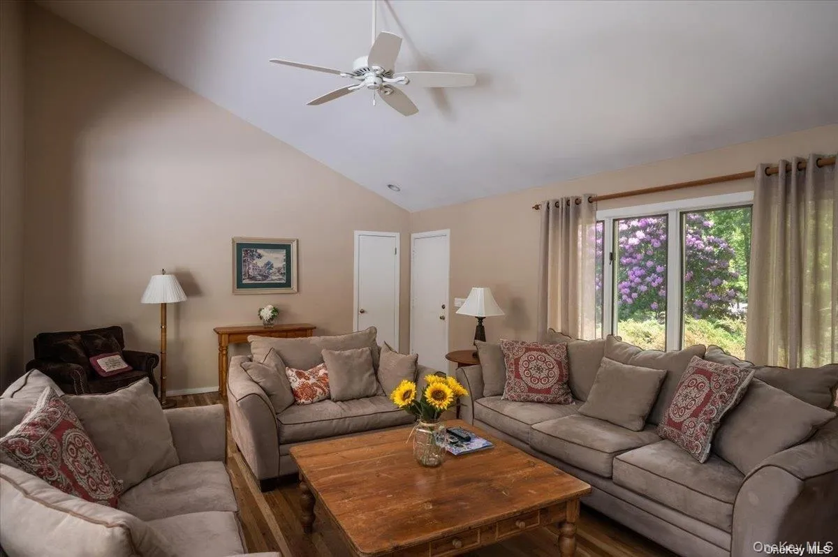 Living area featuring vaulted ceilings, wood-finish flooring, and a ceiling fan Living area featuring vaulted ceilings, wood-finish flooring, and a ceiling fan