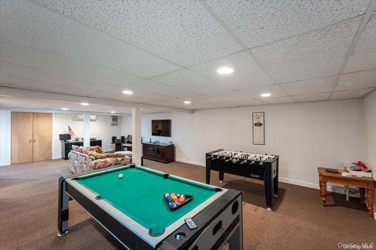 Spacious recreational room featuring recessed lighting, a drop ceiling, and wood-finish bi-fold doors Spacious recreational room featuring recessed lighting, a drop ceiling, and wood-finish bi-fold doors