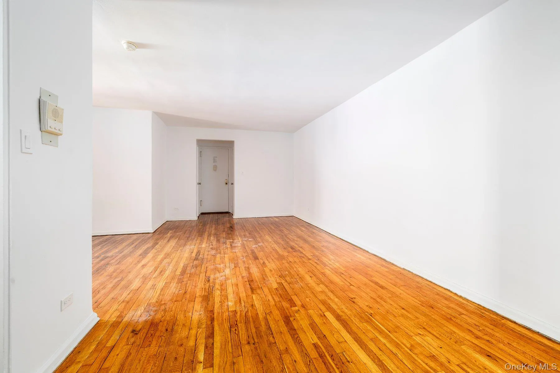 Expansive room with polished wood flooring and bright white walls Expansive room with polished wood flooring and bright white walls